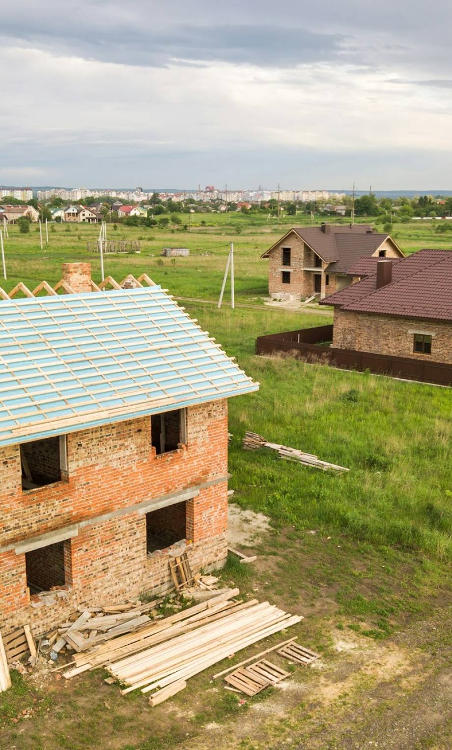 Aerial view of a brick house with wooden roof frame under construction. Aerial view of a brick house with wooden roof frame under construction.