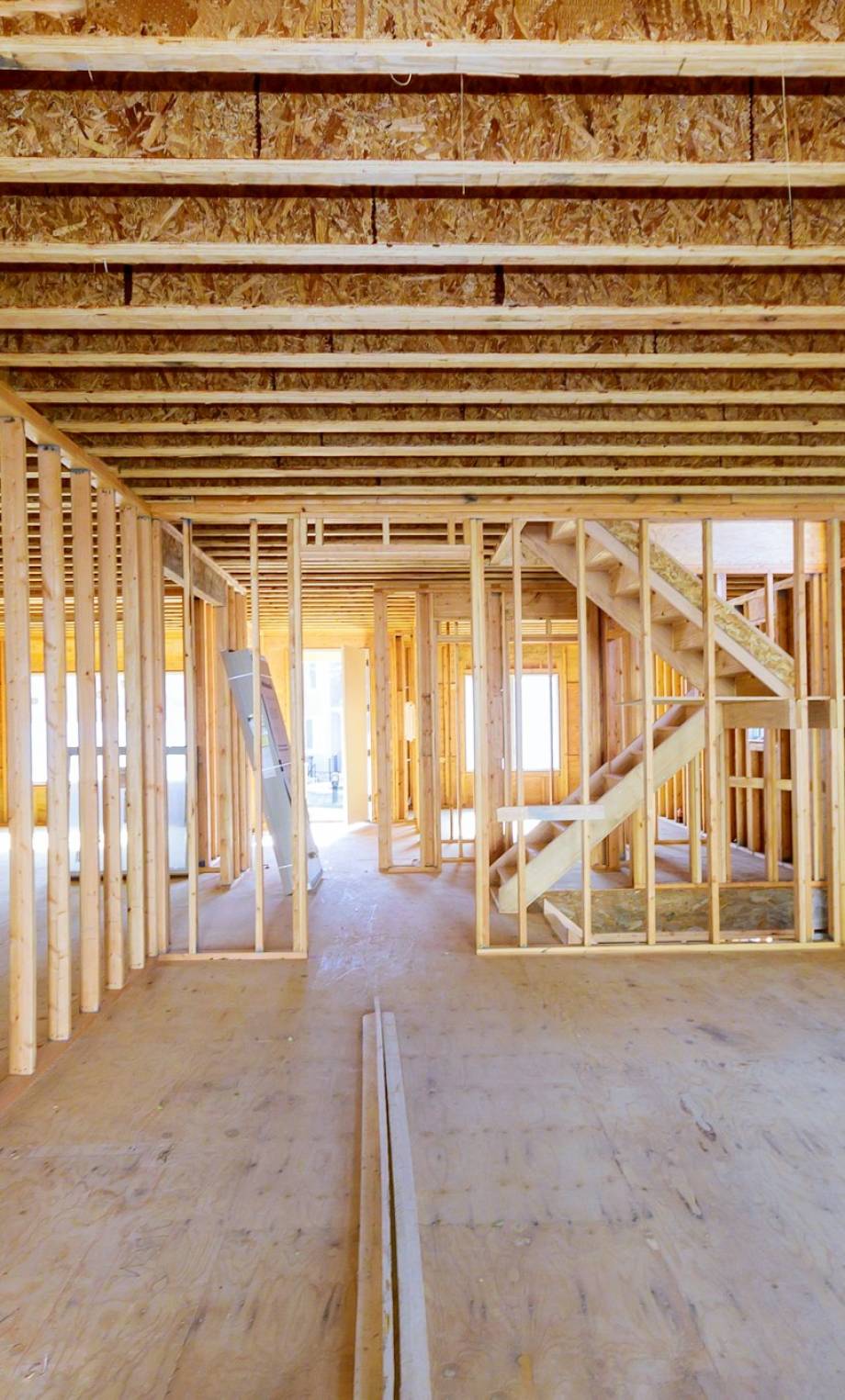 Building construction, wood framing new home under construction roof being built against blue sky Building construction, wood framing new home under construction roof being built against blue sky